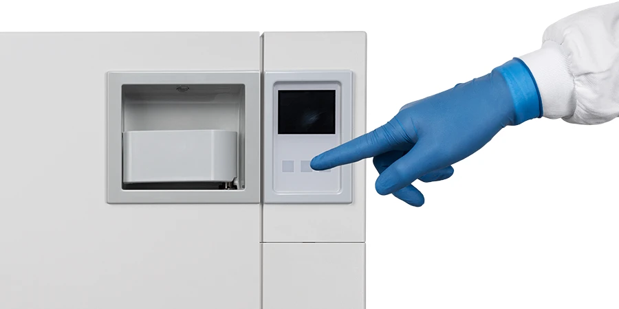 main gantée pointant l'éran de l'Autoclave Euronda E6